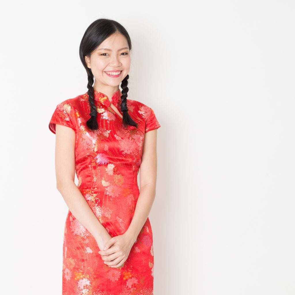Coiffures asiatiques : Modèle asiatique aux cheveux bruns lisses avec des nattes tressées, portant une tenue traditionnelle rouge à fleurs.