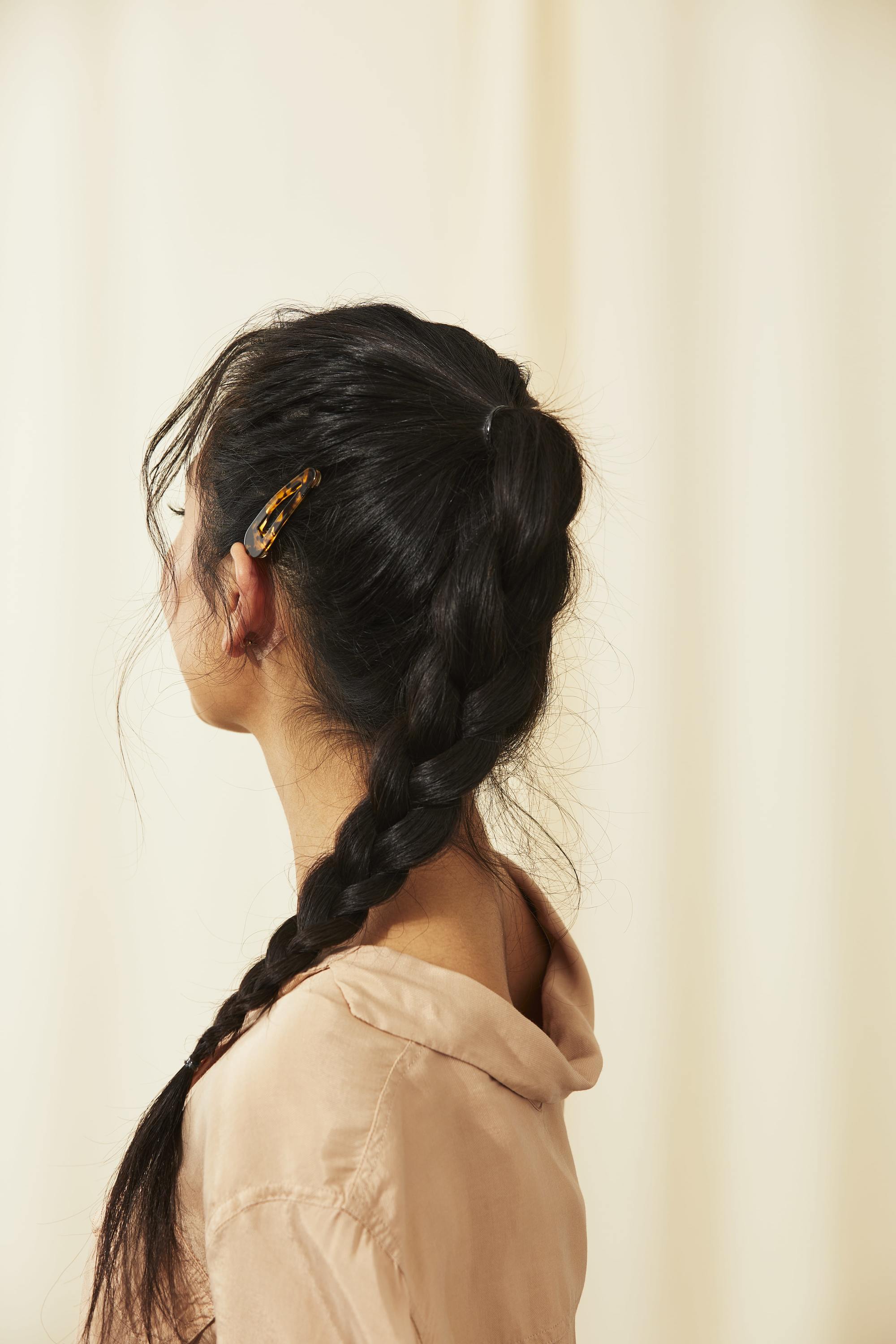 Femme aux longs cheveux asiatiques tressés coiffés en queue de cheval tressée avec une pince à cheveux.