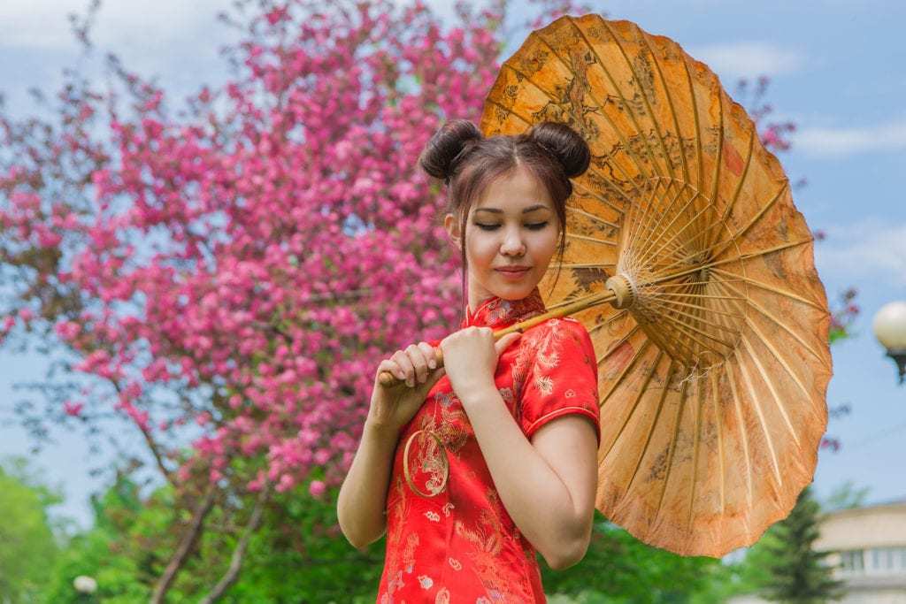 Coiffures asiatiques : Femme asiatique aux cheveux bruns et raides, coiffés en chignon spatial, portant une tenue traditionnelle rouge.