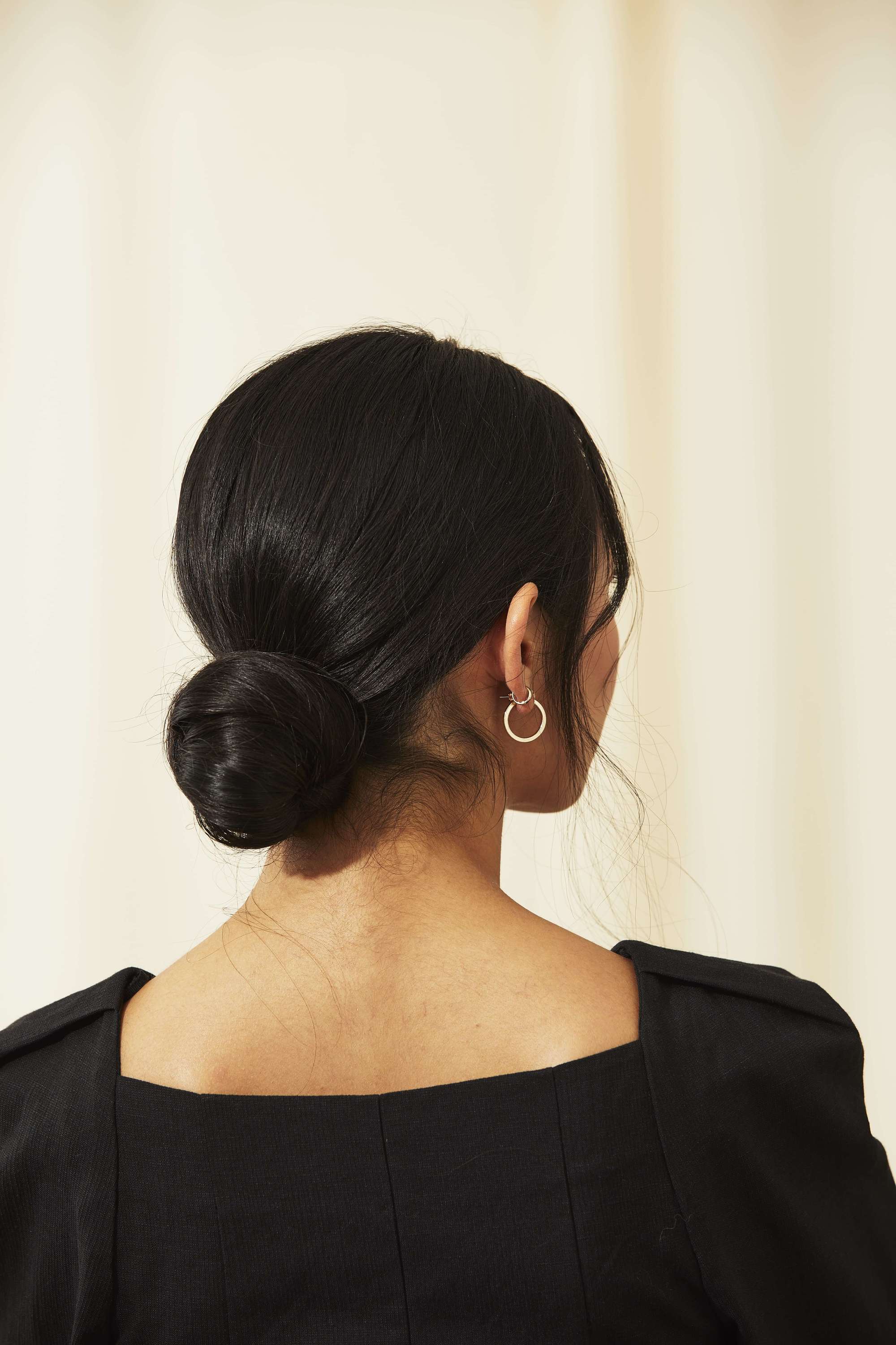Femme aux cheveux asiatiques foncés coiffés en un chignon bas noué.