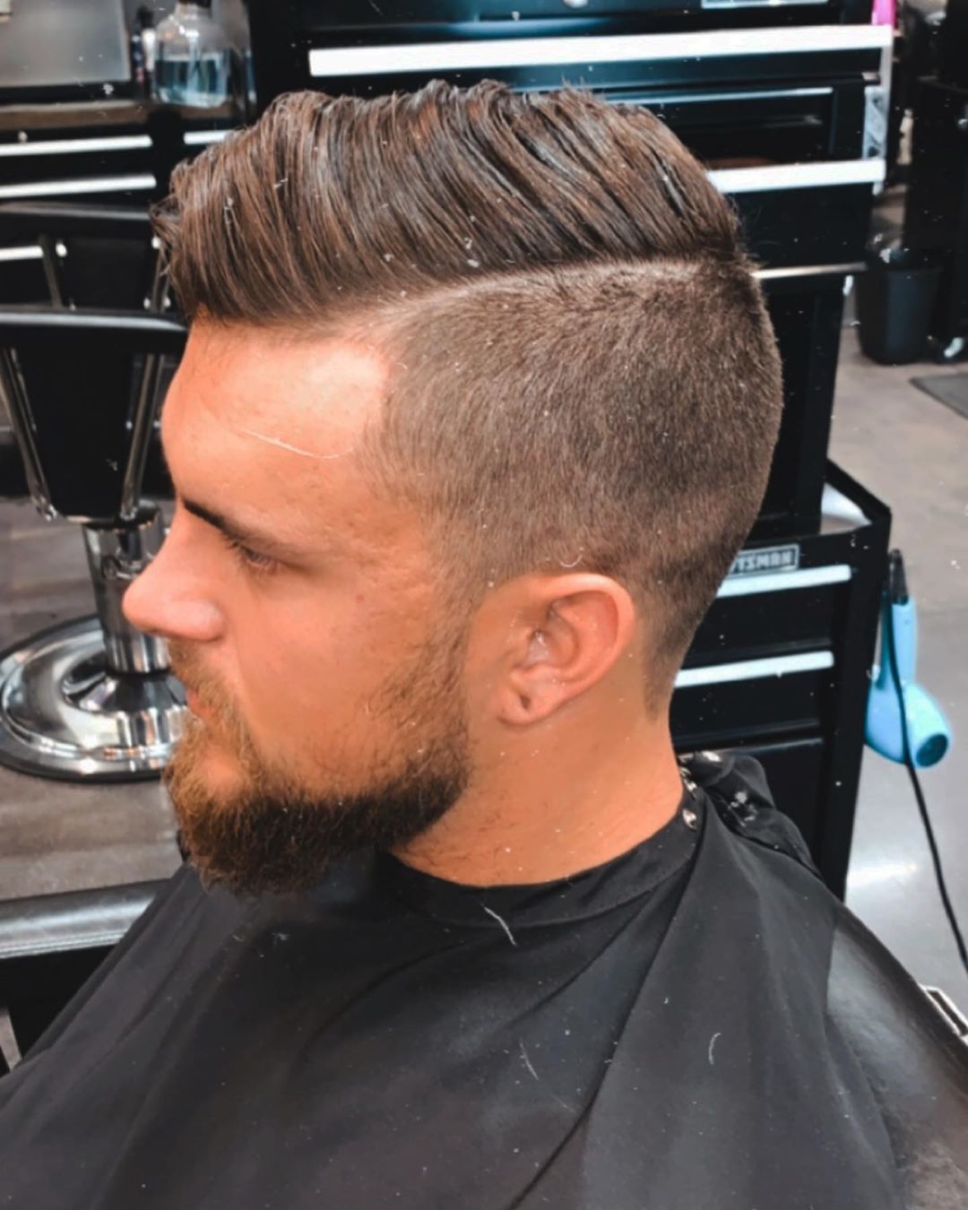 Homme aux cheveux bruns avec un peigne et une sous-coupe.