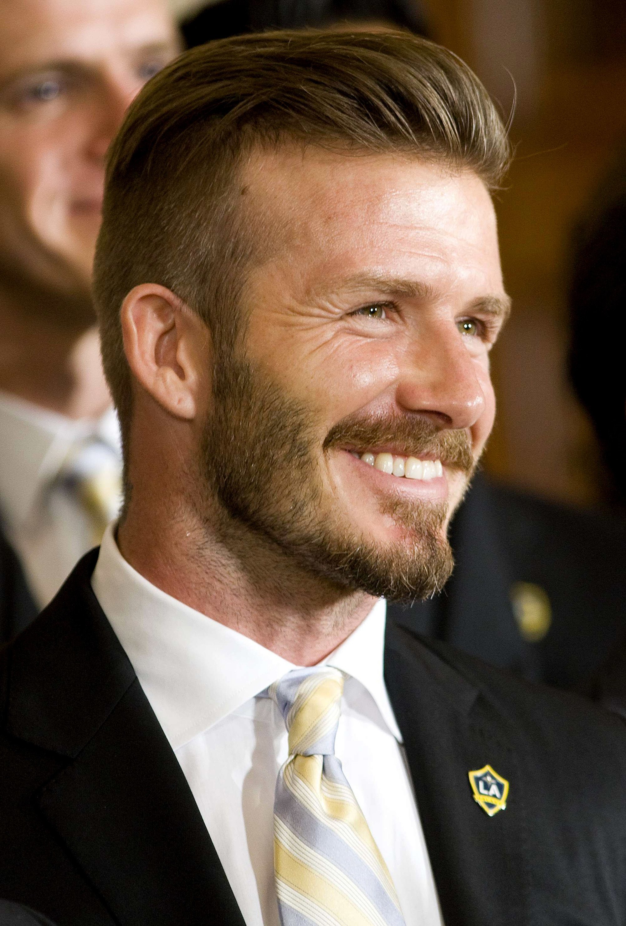 David Beckham avec des cheveux balayés en arrière avec une sous-coupe et une barbe.