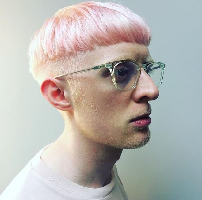 Vue de côté d'une coupe de cheveux rose pastel sur un homme à lunettes.