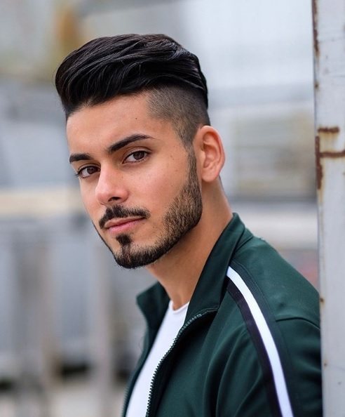 Photo de style urbain d'un homme aux cheveux bruns coiffés en pompadour avec une sous-coupe.