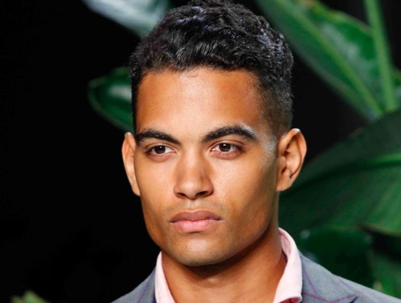 Vue de face d'un homme aux cheveux noirs ondulés et à la coupe courte. 