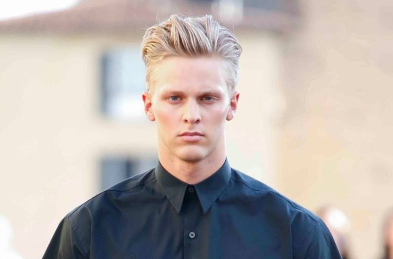 Vue de face d'un homme aux cheveux blonds, avec une touffe et une sous-coupe. 