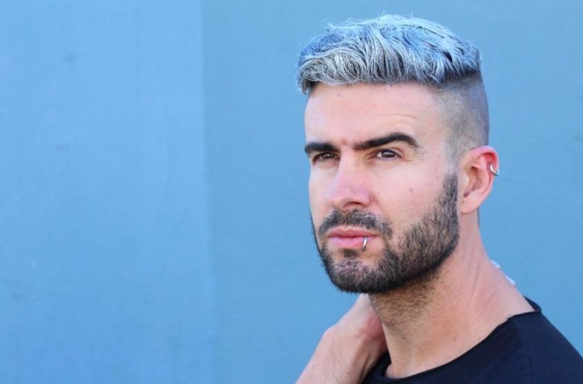 Vue de face d'un homme aux cheveux colorés et à la barbe.