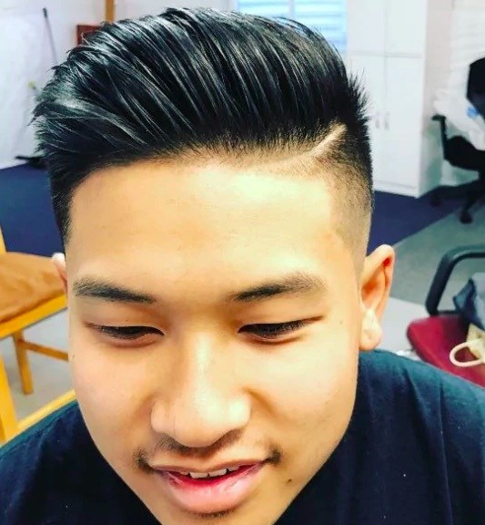 Vue de face d'un homme avec des cheveux noirs et une coupe subtile. 