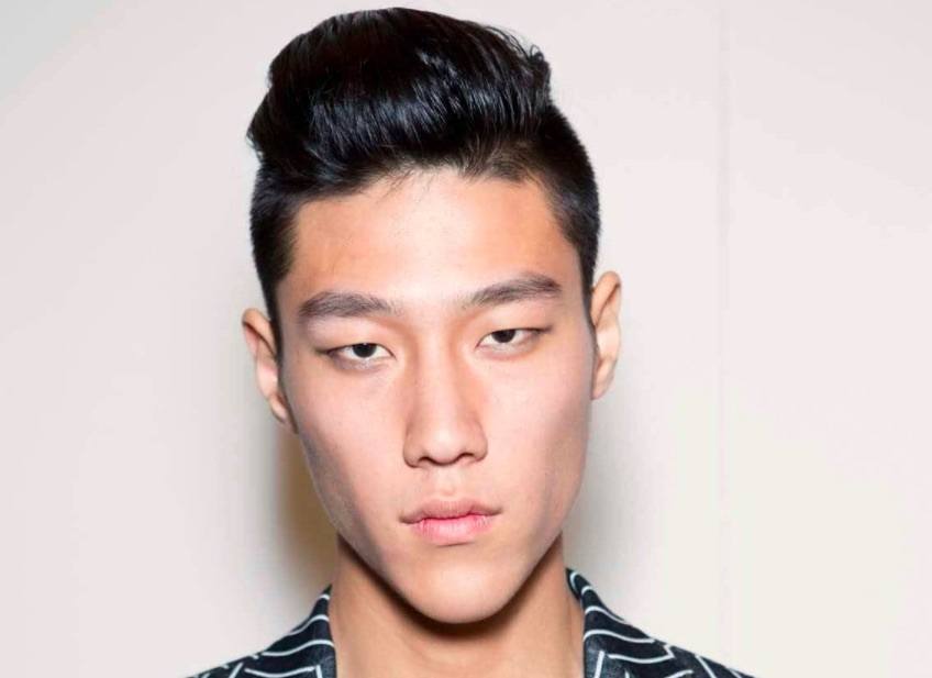 Image de face d'un homme avec des cheveux noirs au look mouillé, avec une sous-coupe et une touffe.