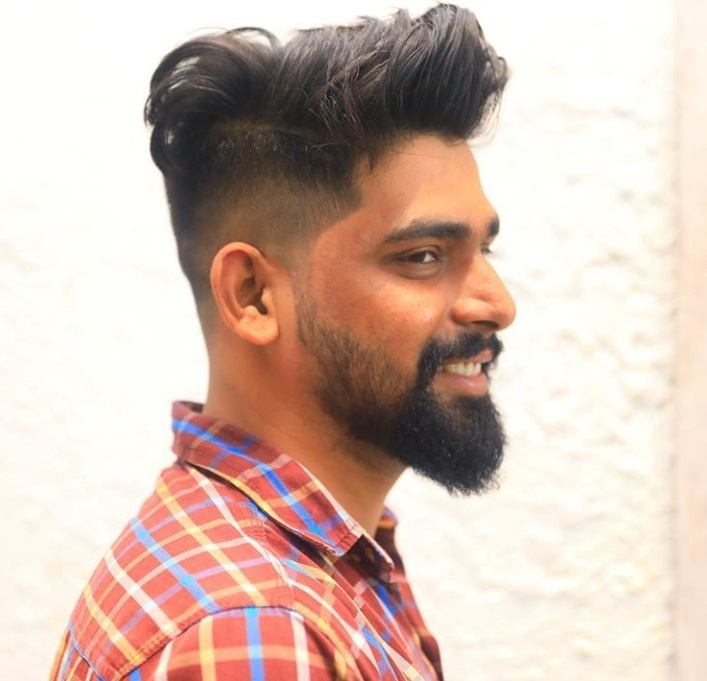 photo d'un modèle masculin portant un costume avec une coupe de cheveux bouclée sur le côté.