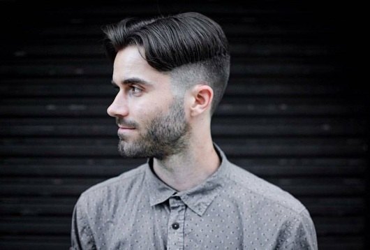 Plan de profil d'un homme brun avec des cheveux en rideau et une sous-coupe.