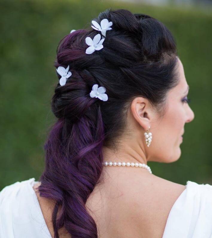 Femme avec des cheveux violets ombragés dans un tissage avec des fleurs ajoutées.