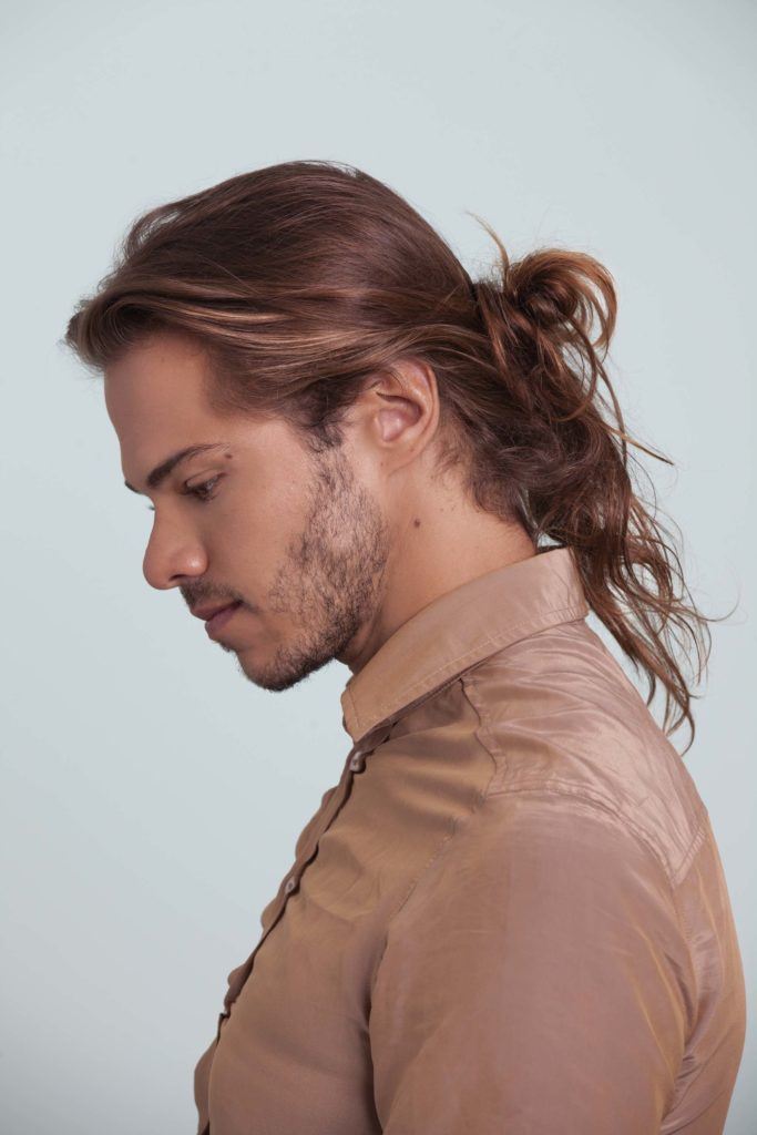 Tutoriel chignon d'homme homme avec chignon d'homme désordonné regardant vers le bas photo de profil.