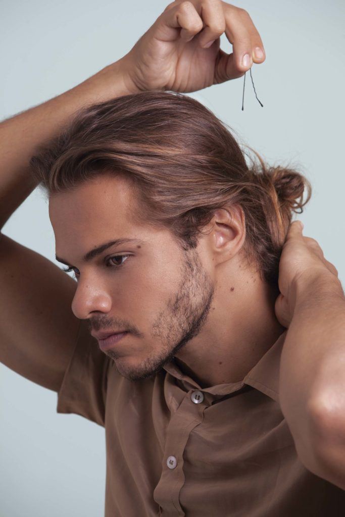un homme avec des cheveux en chignon regardant de côté