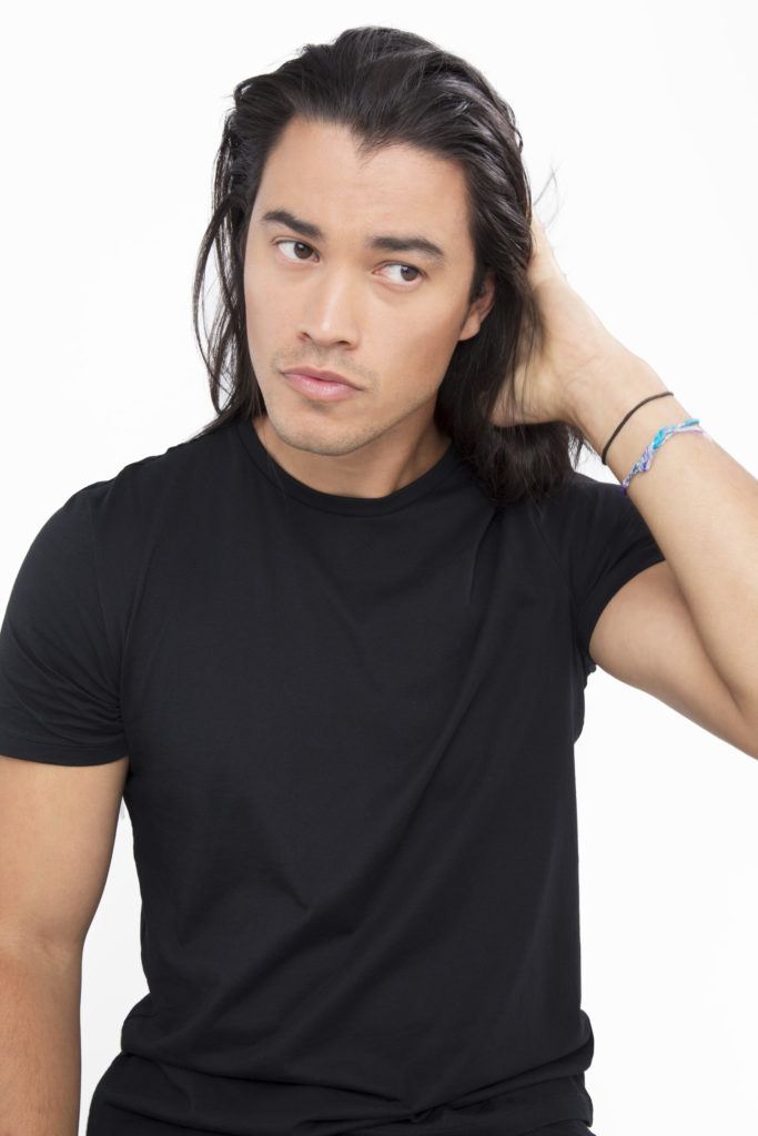 Homme aux cheveux noirs appliquant du produit sur ses cheveux bruns foncés.
