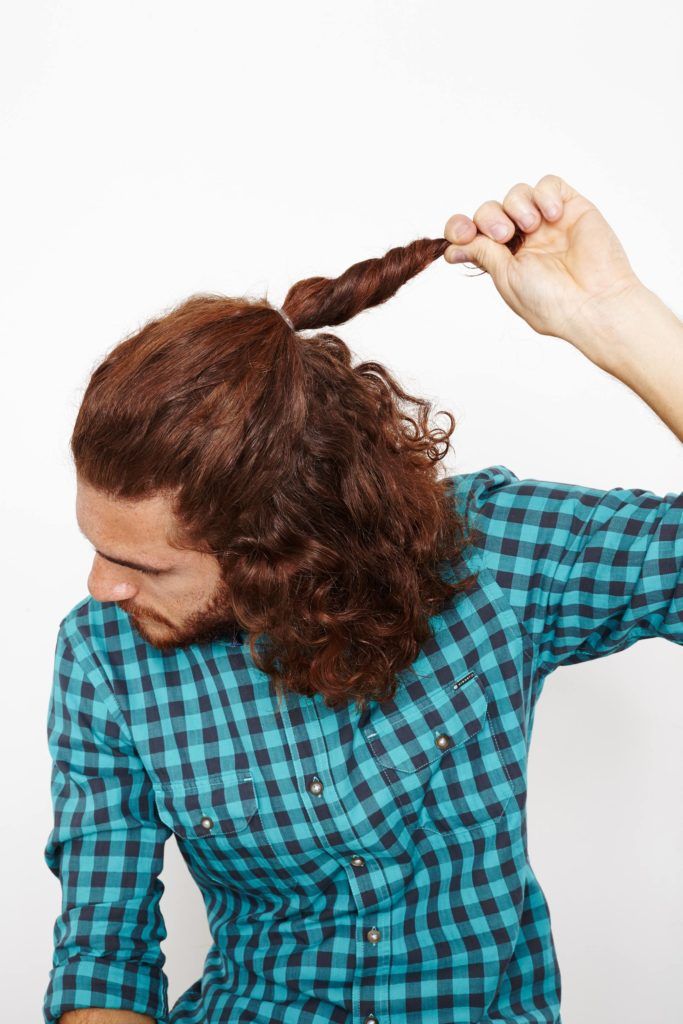 queue de cheval mi-haute mi-bas sur un homme aux cheveux bouclés