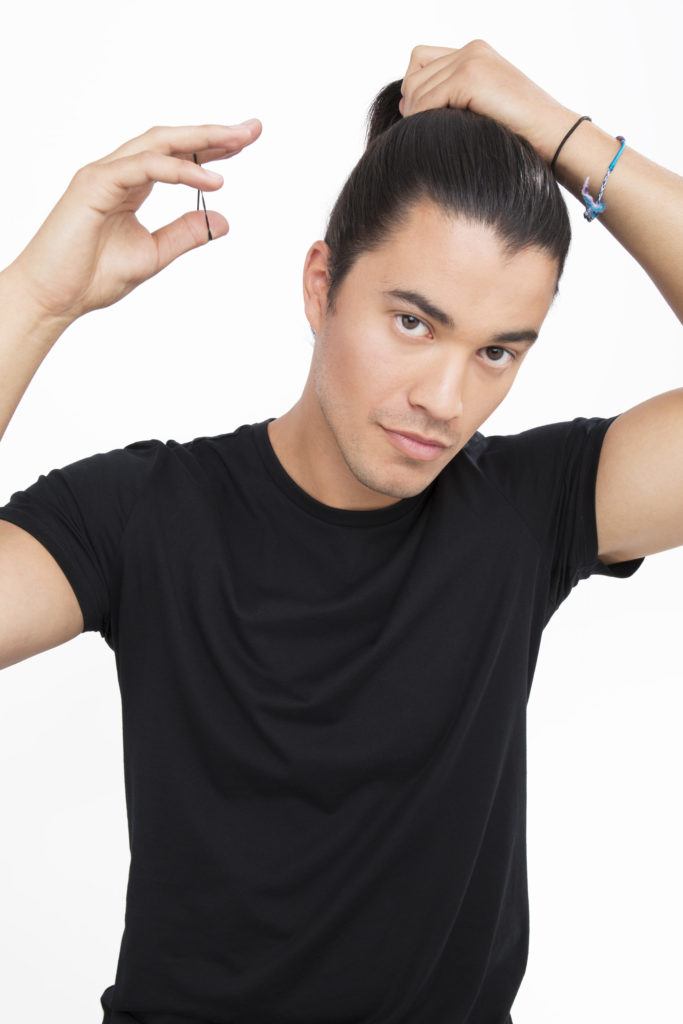 Homme aux cheveux noirs rassemblant ses cheveux bruns foncés