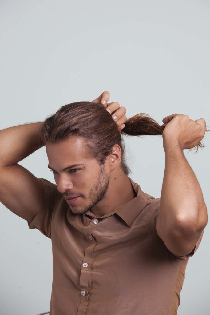 Tutoriel chignon d'homme homme avec des cheveux bruns faisant une queue de cheval.