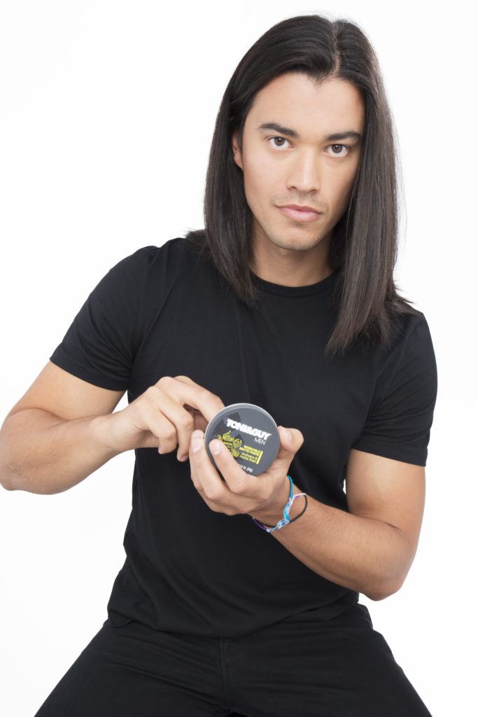 Un homme aux cheveux bruns ramassant du produit pour ses cheveux bruns.