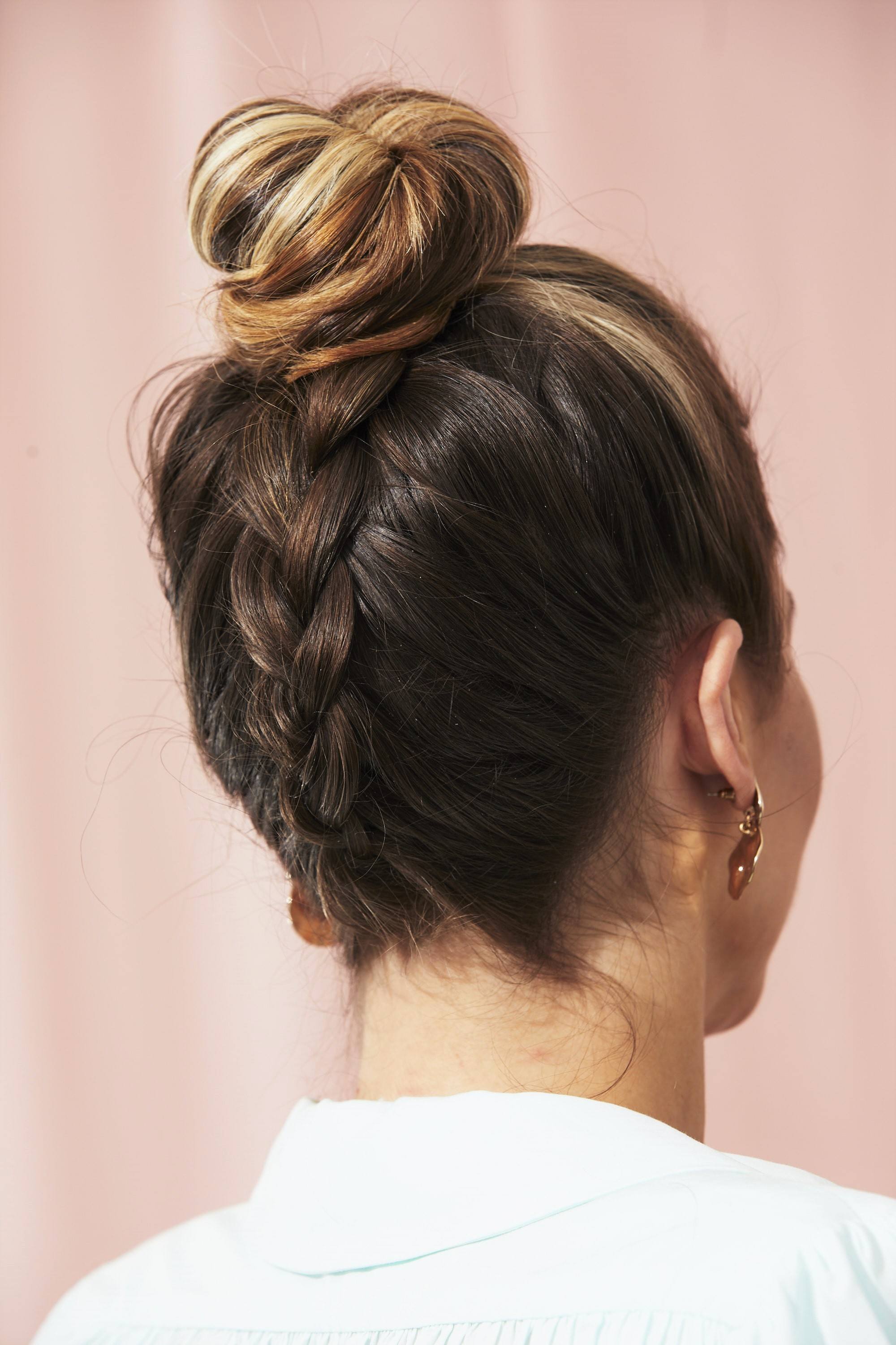 Femme aux cheveux bruns avec un chignon tressé à l'envers.