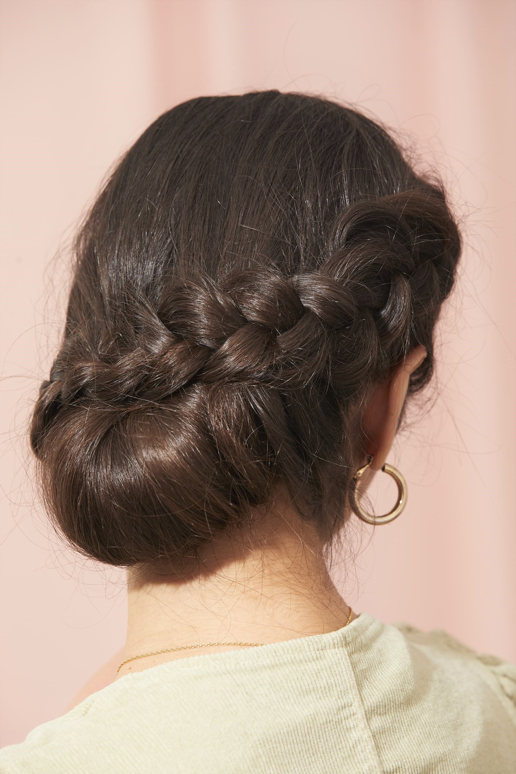 Femme brune avec un chignon tressé enveloppant.