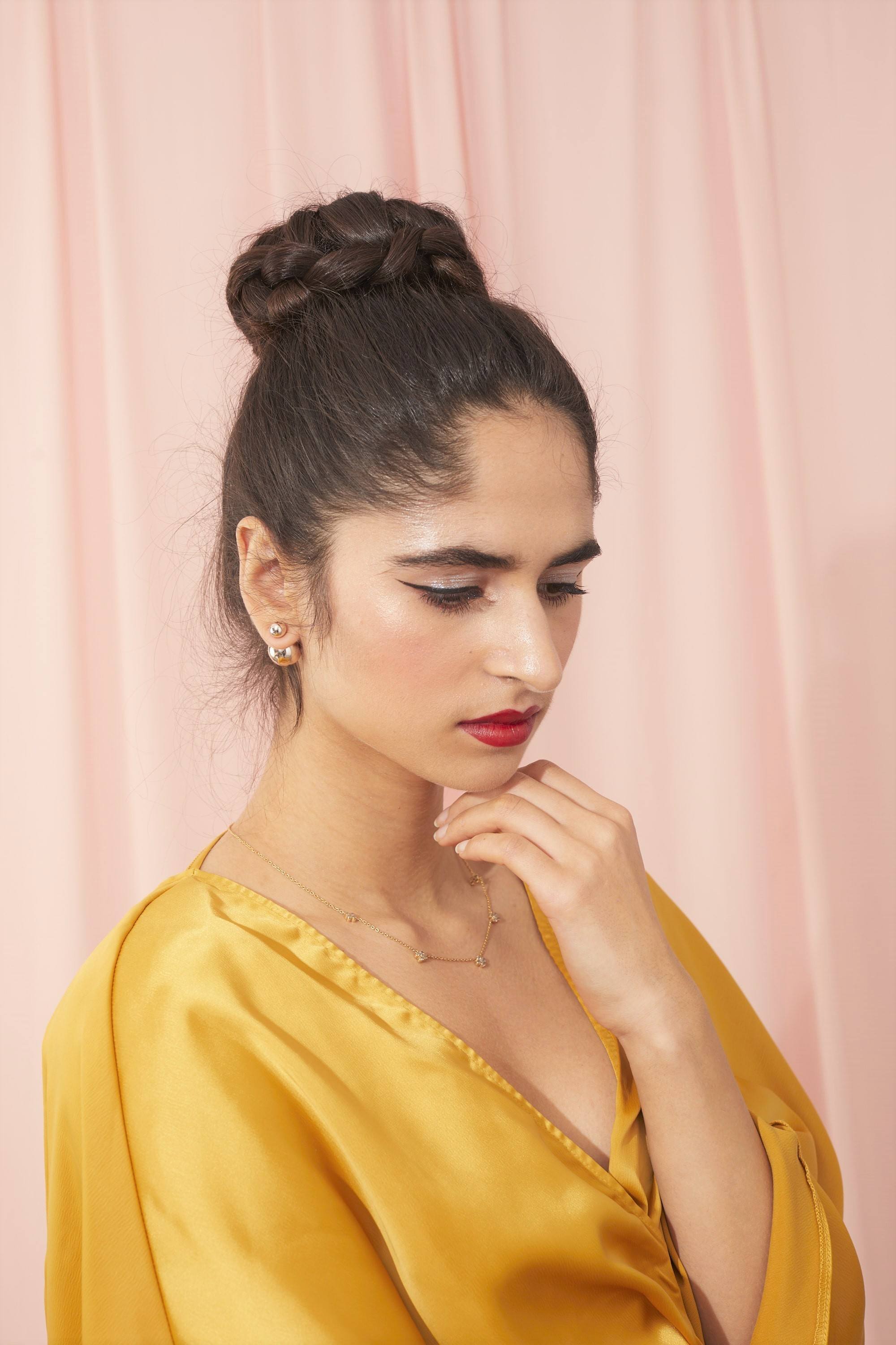 Femme avec des cheveux bruns foncés dans un haut chignon de ballerine tressé.