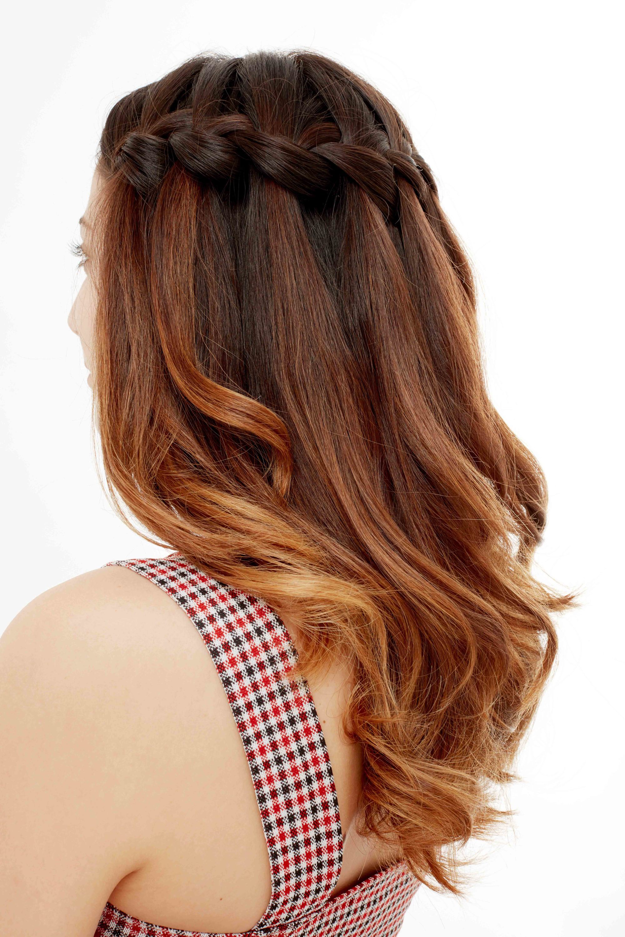 Plan de côté d'un mannequin avec des cheveux moyens ondulés de couleur brune à rouge, coiffés en une tresse en cascade, posant dans le studio Poudre de Rose UK.