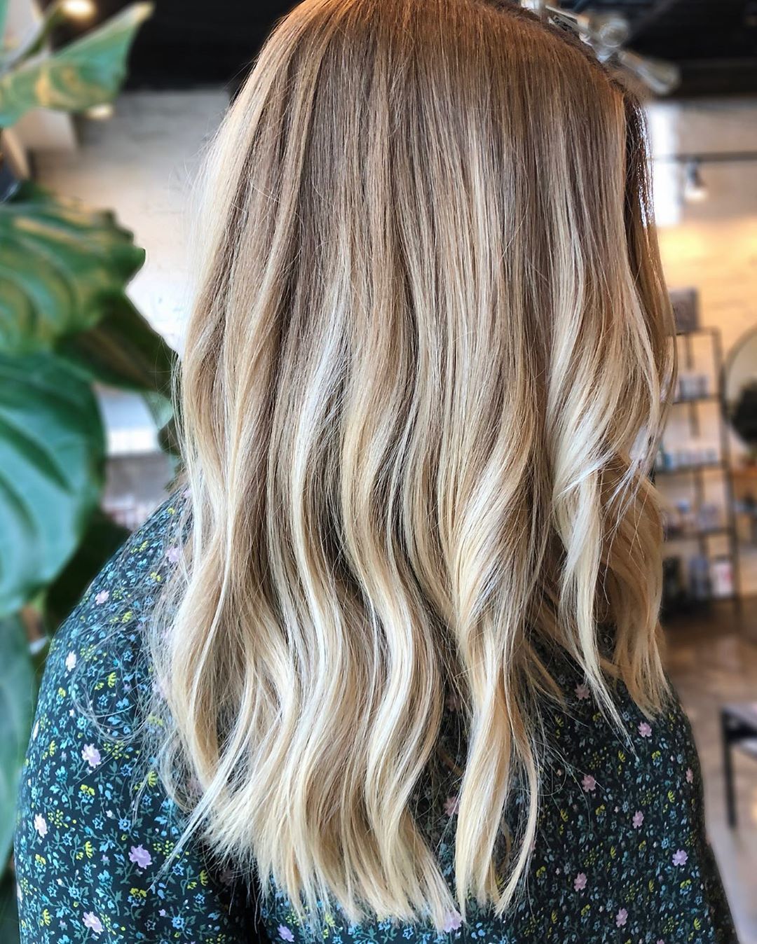 Femme avec des cheveux mi-longs ondulés blond miel avec des mèches blond clair.