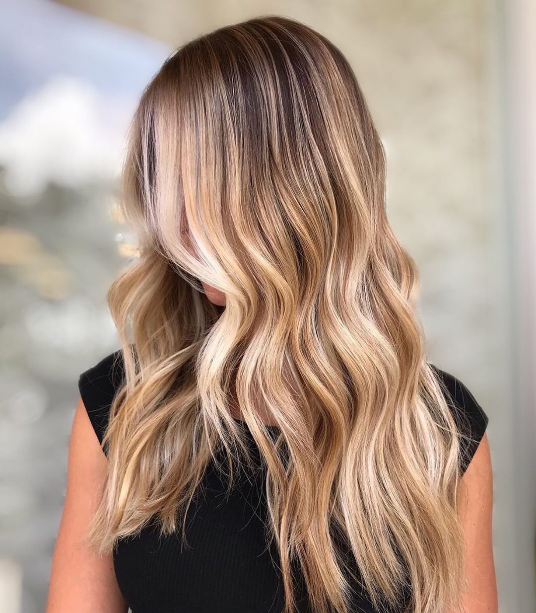 Femme aux longs cheveux ondulés blond miel méché