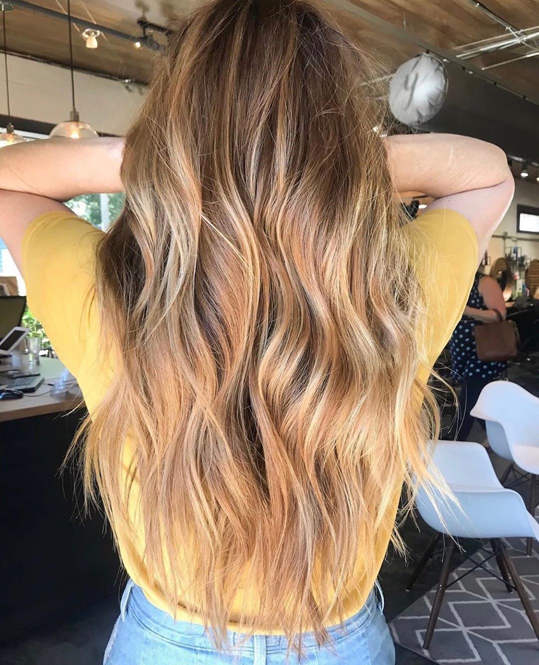 Femme avec de longs cheveux balayés blond miel ondulés.