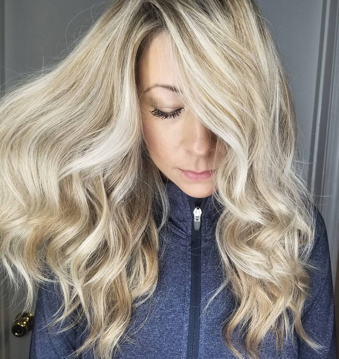 Femme avec des cheveux blond miel clair bouclés avec une raie sur le côté.