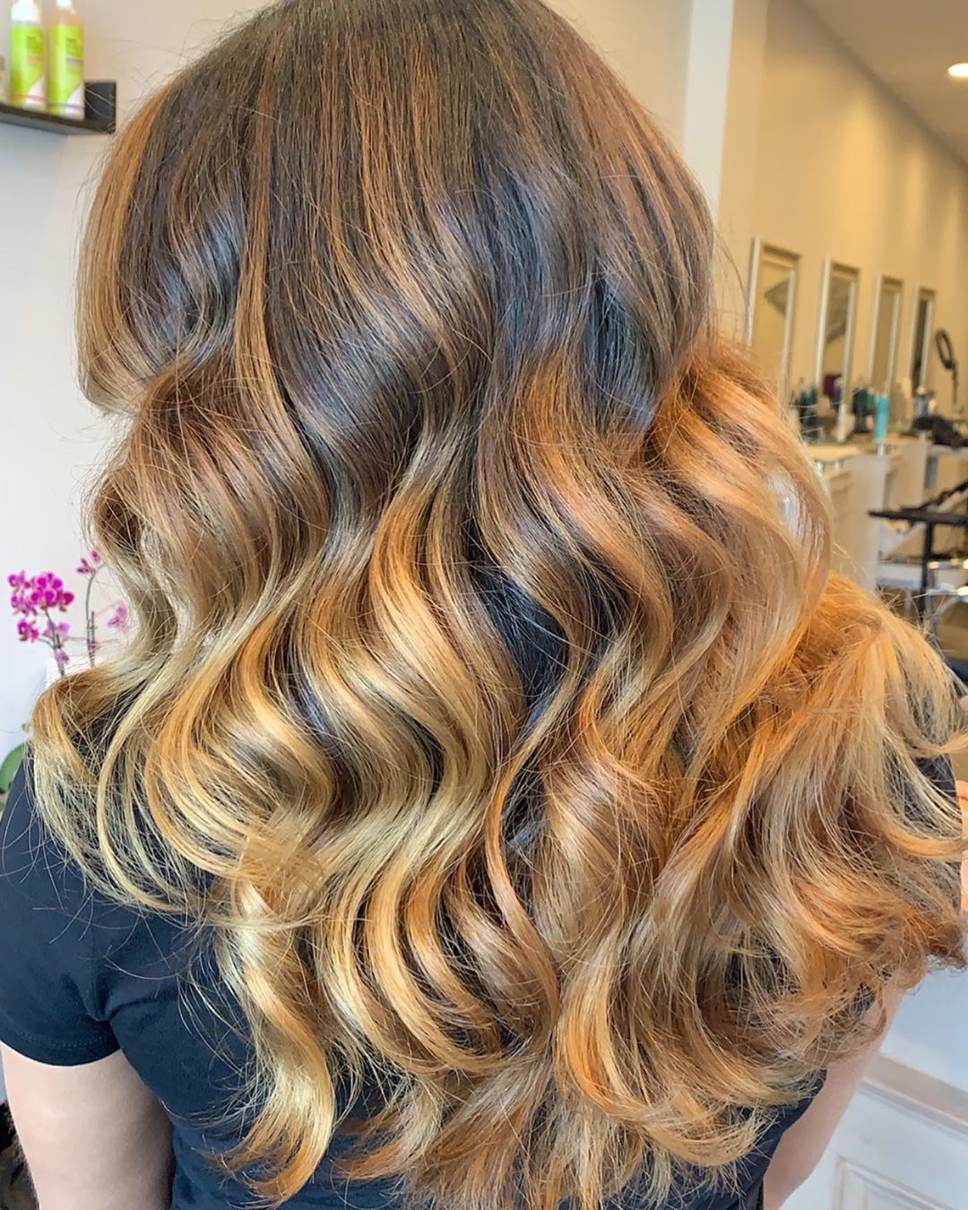 Femme avec des cheveux longs, ondulés, caramel et blond miel.