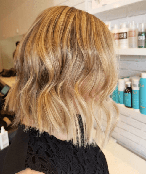 Vue de côté d'une femme dont les cheveux sont de couleur miel et ondulés. 