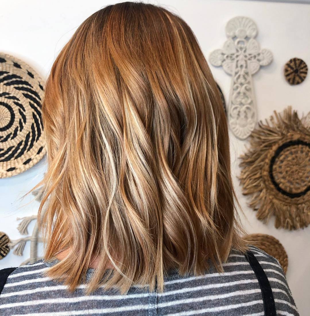Femme avec une coupe de cheveux ondulée rouge miel clair