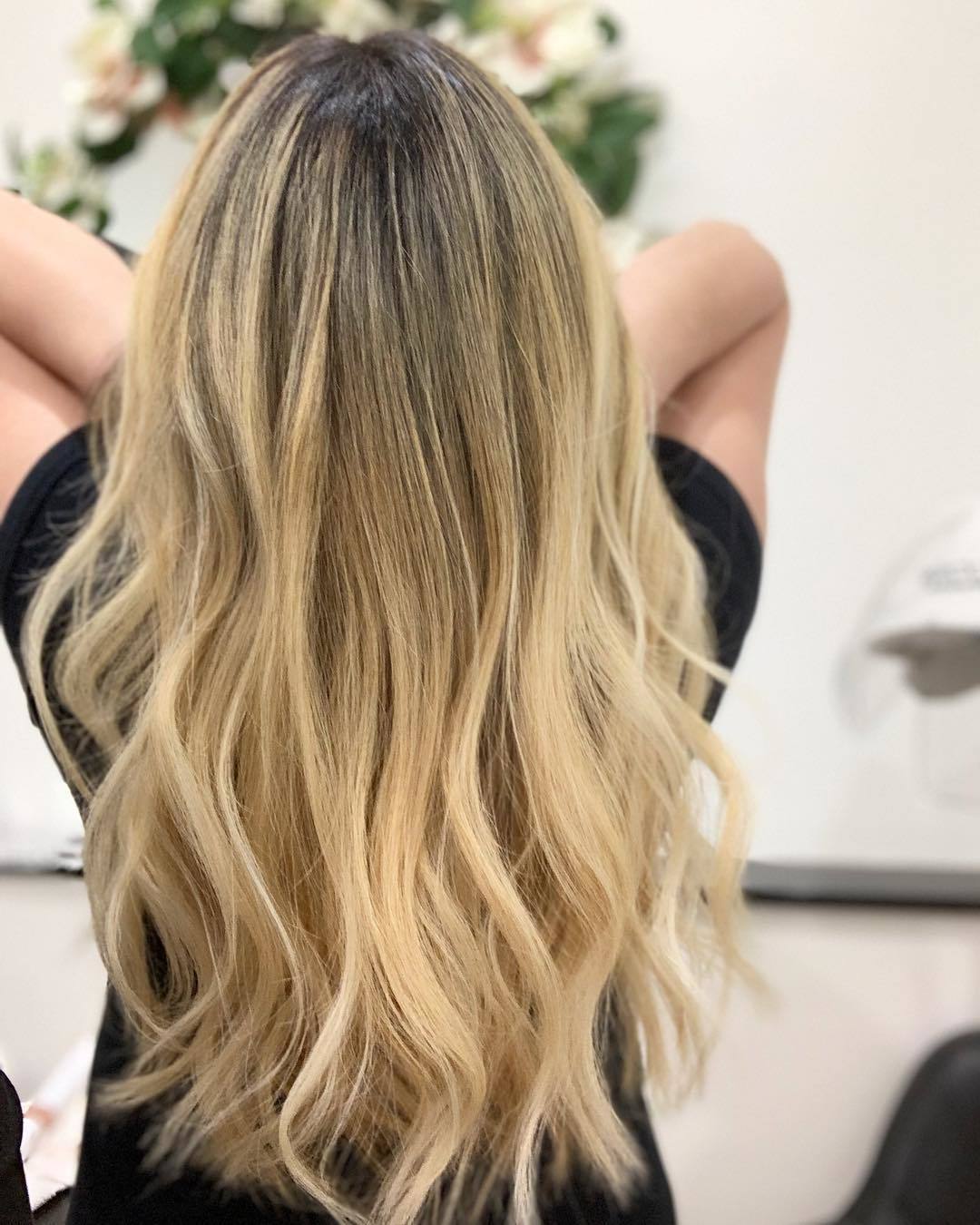Femme avec de longs cheveux blond platine miel ondulés.