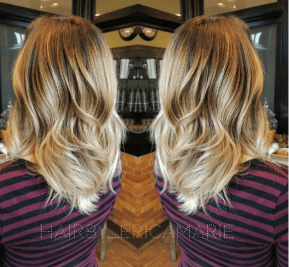 Vue arrière d'une femme avec des cheveux ondulés - racines foncées et cheveux blond miel.