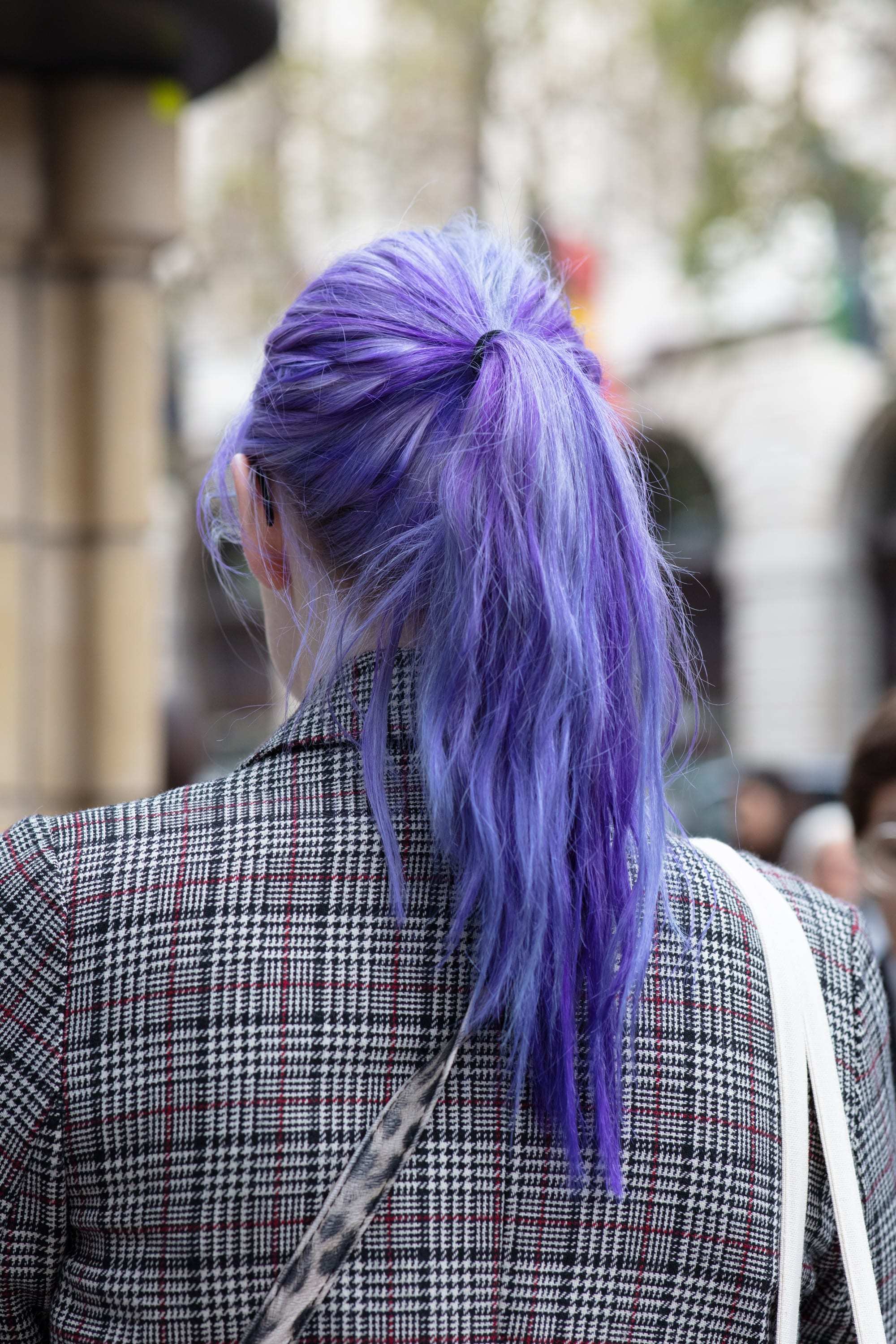 Traitement à l'huile chaude pour cheveux abîmés : Femme avec une queue de cheval violette, portant un blazer à carreaux à l'extérieur.