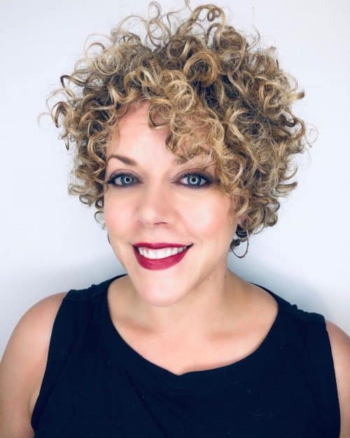cheveux courts et bouclés avec une frange balayée sur le côté