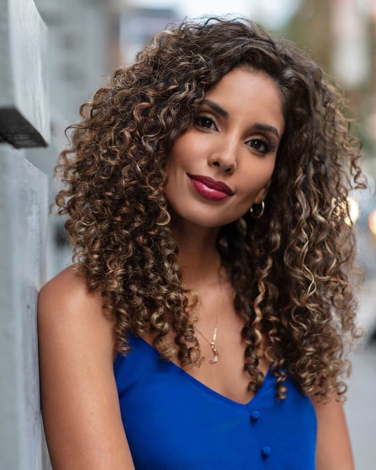 Coiffure bouclée de Deva pour les cheveux mi-longs.