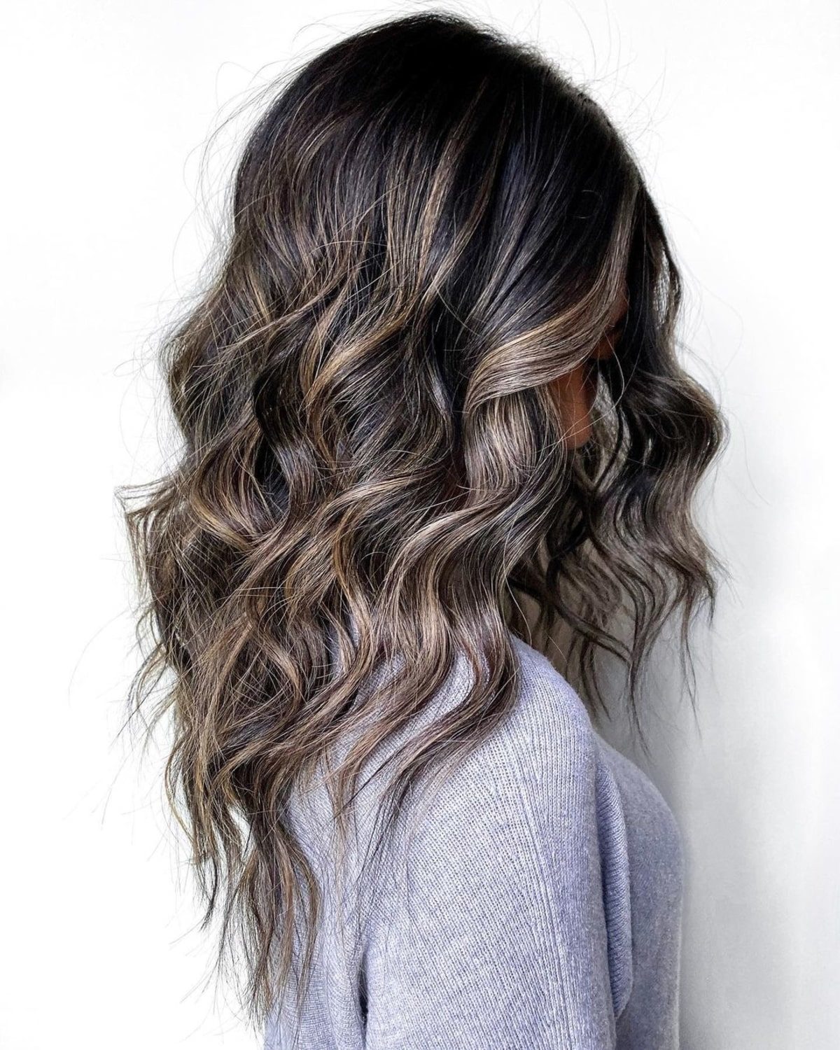Cheveux foncés avec des mèches blondes et un balayage caramel.