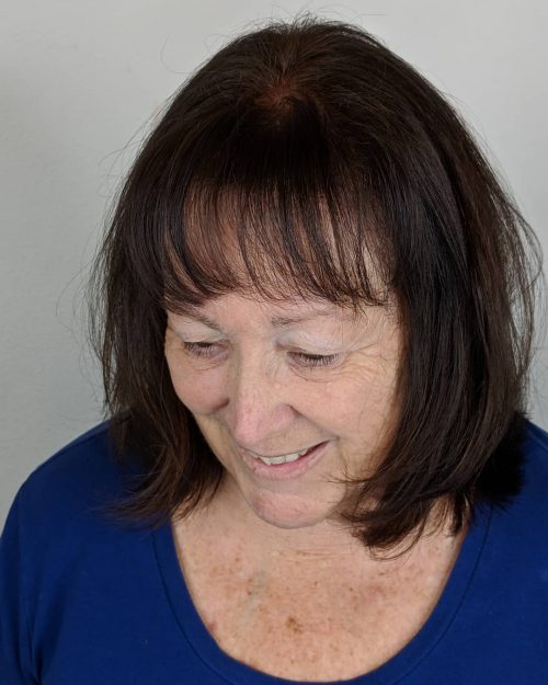 Coiffure mi-longue avec frange et dégradés pour les femmes plus âgées.