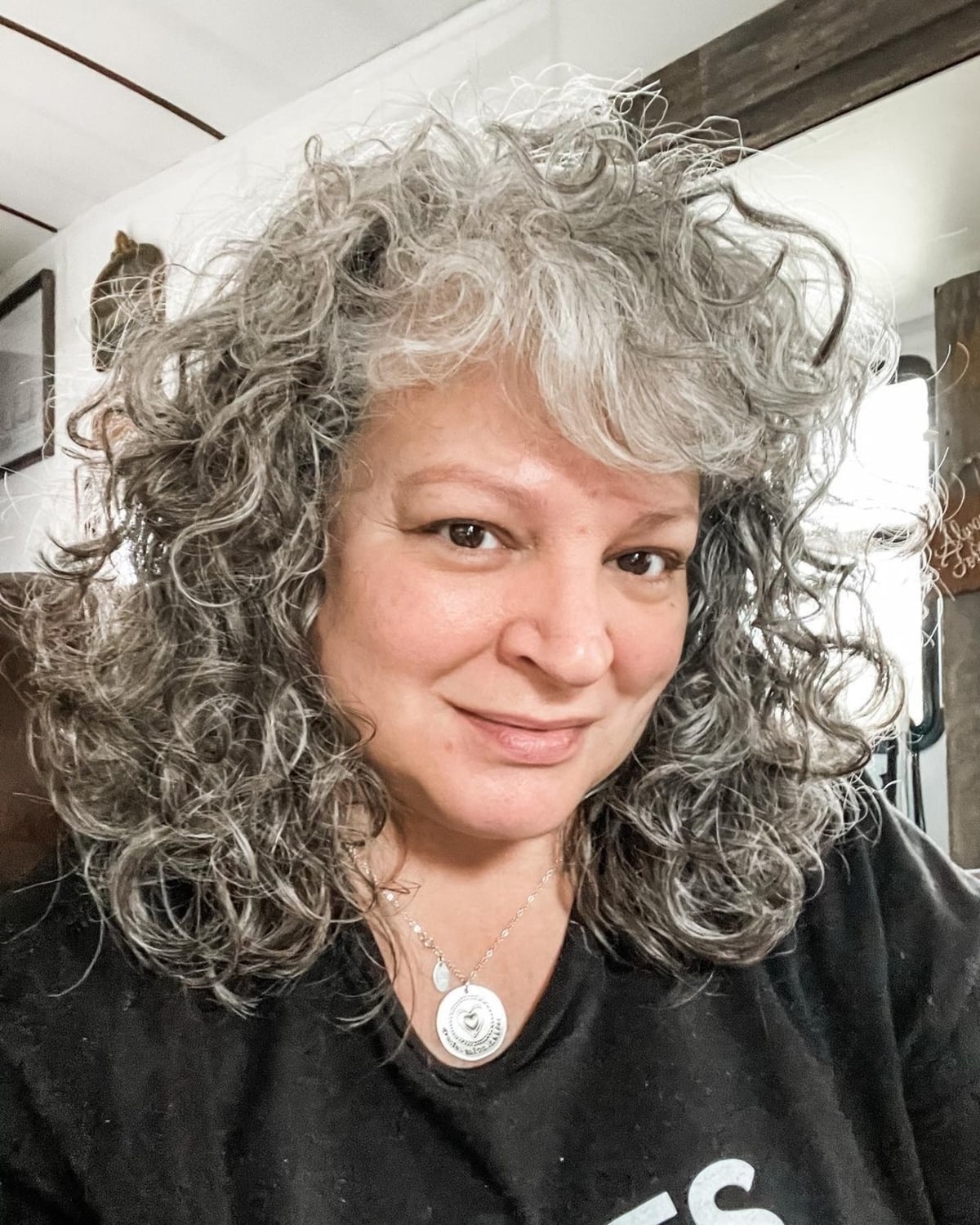 Coupe mi-longue pour les femmes de la cinquantaine aux cheveux bouclés.
