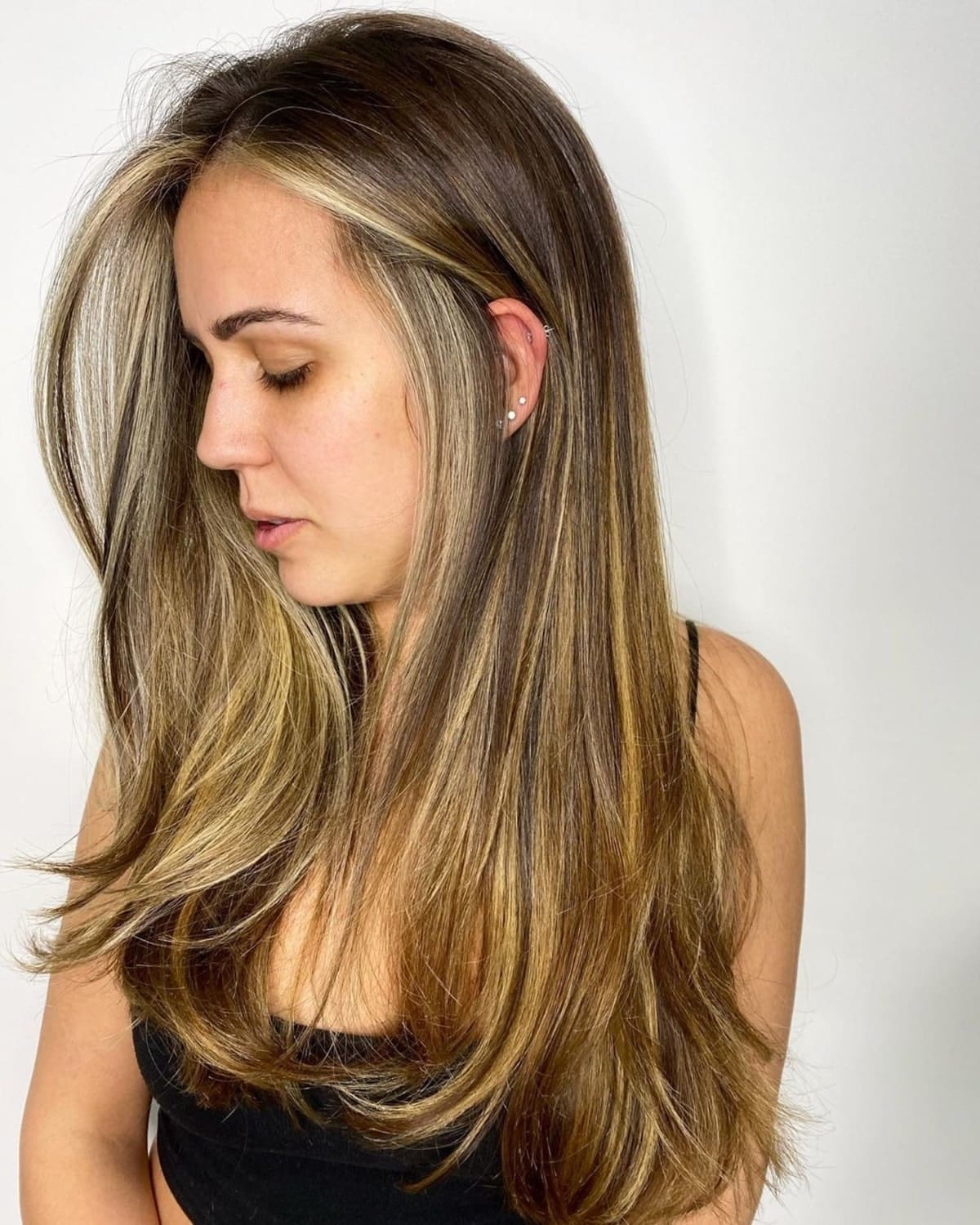 Mèches blond doré sur cheveux bruns foncés.