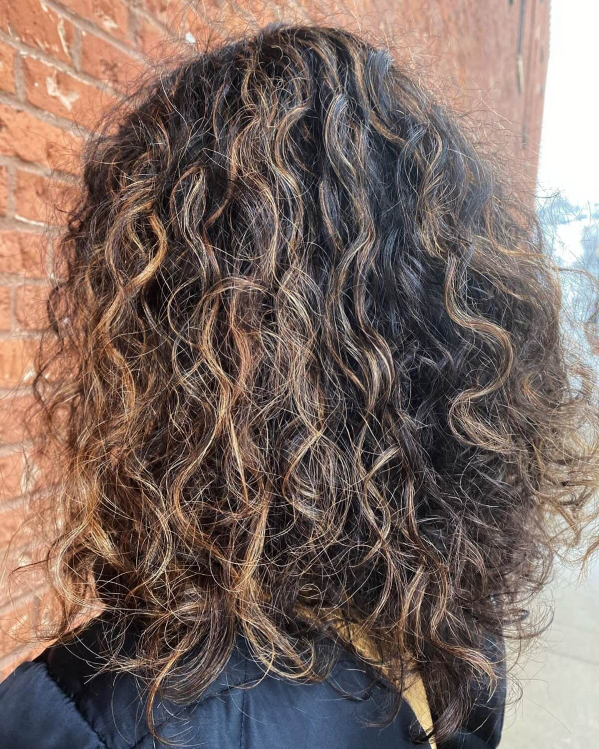 cheveux bouclés brun foncé avec des reflets caramel
