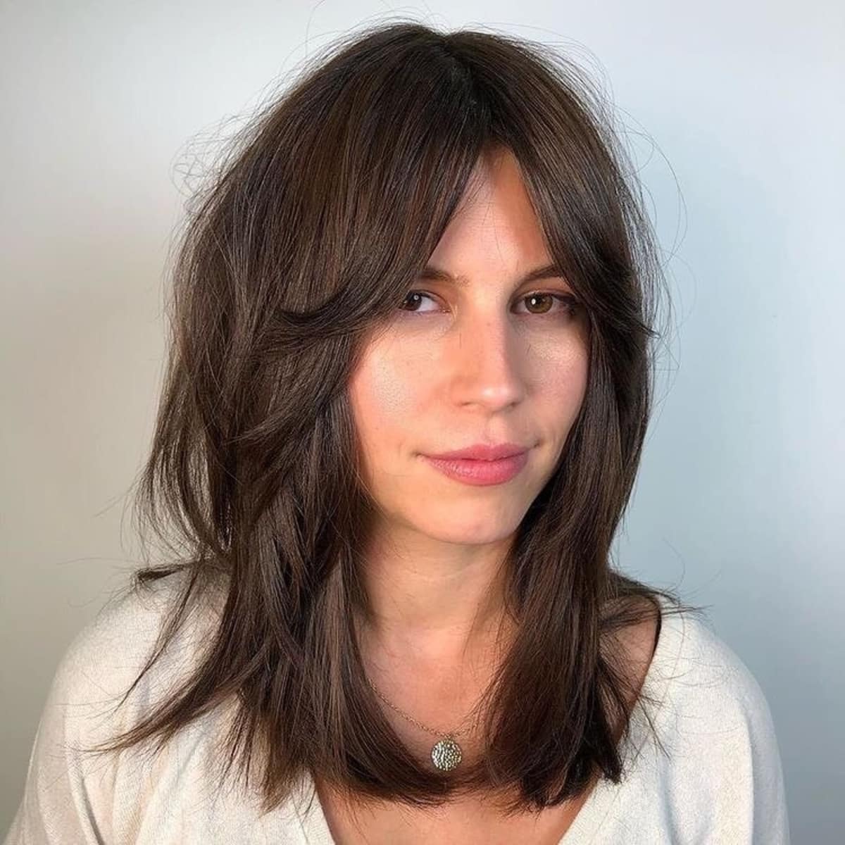 Frange rideau encadrant le visage pour les cheveux mi-longs.