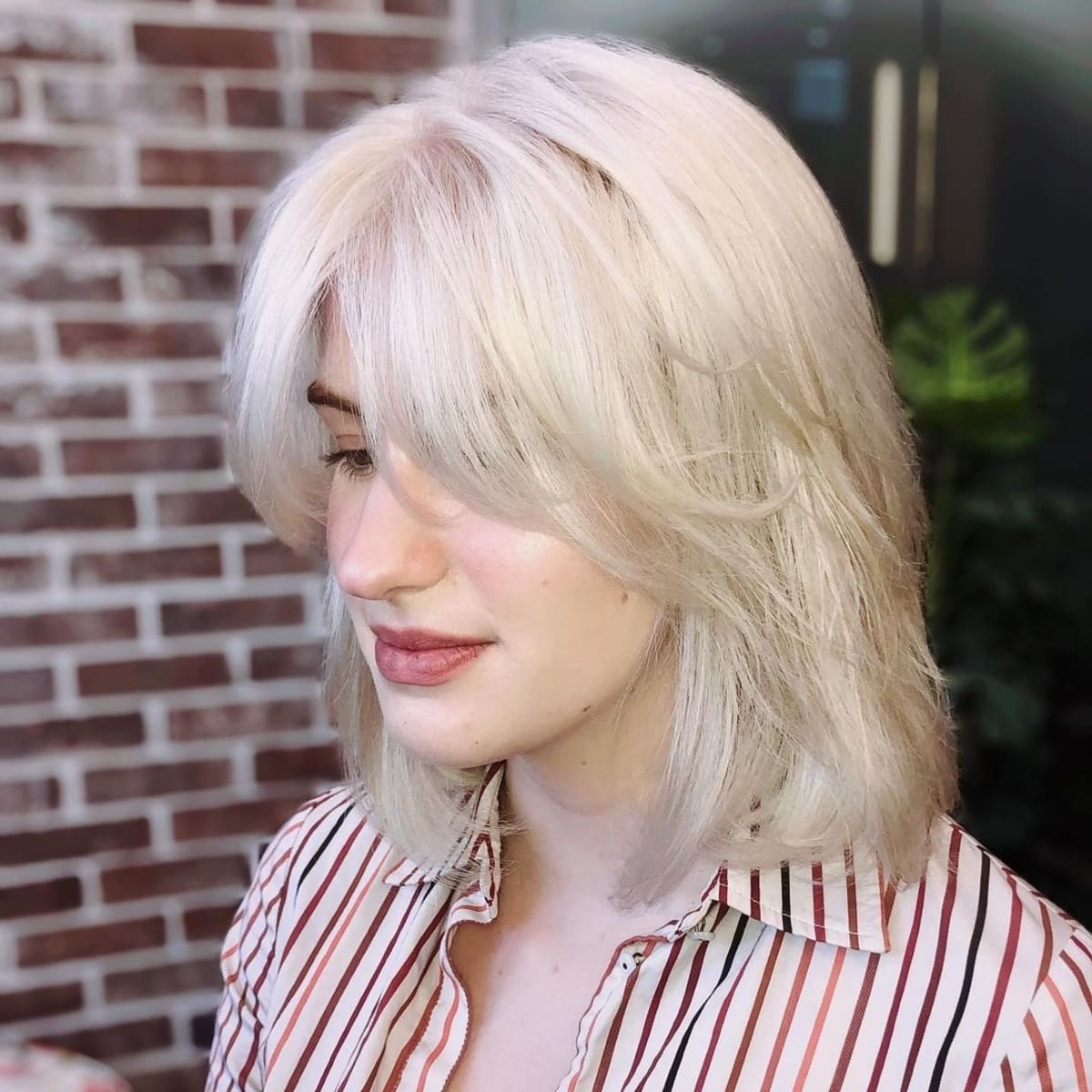 Coiffure droite sur l'épaule avec une frange en rideau.