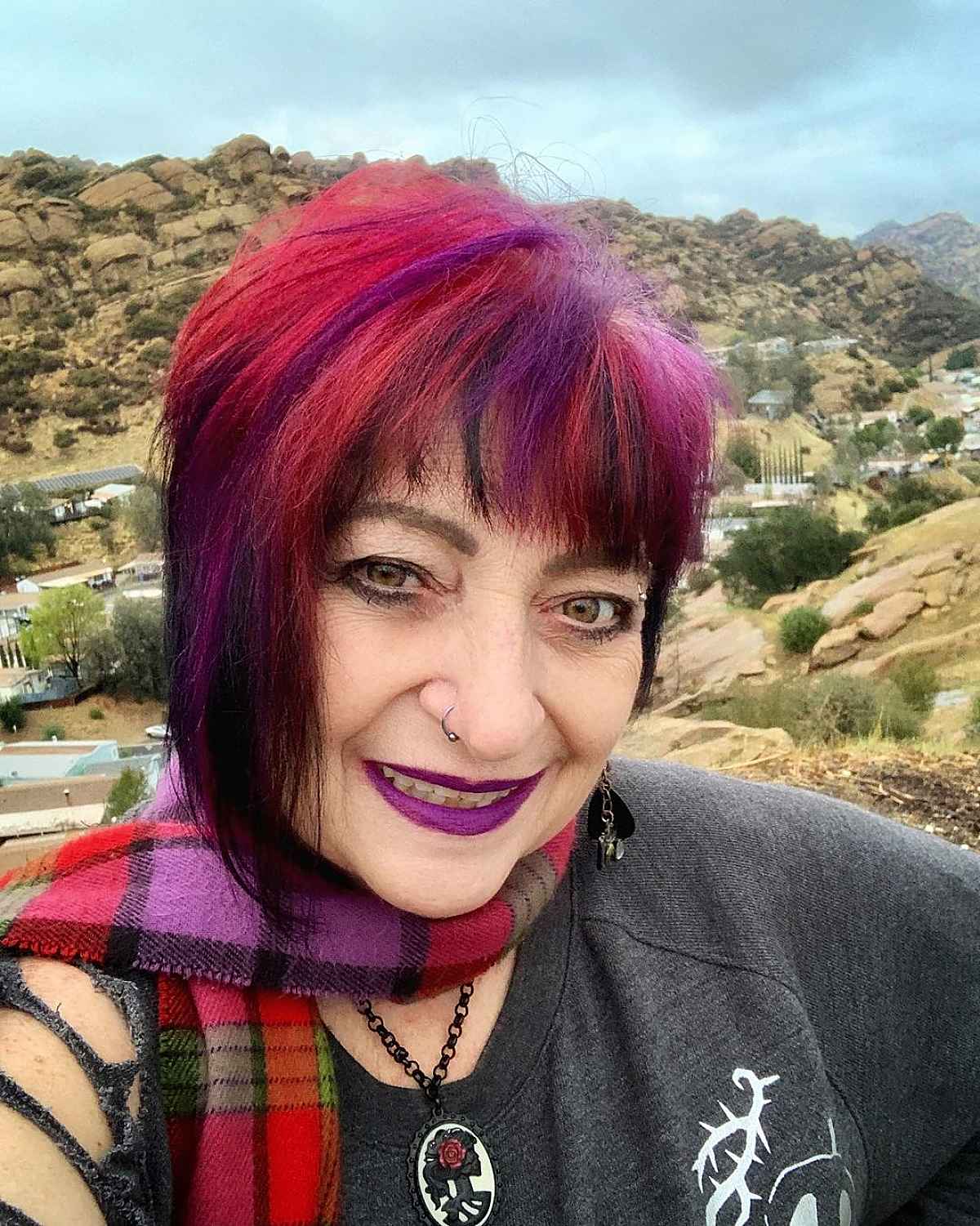 Femme de plus de 60 ans avec une coupe de cheveux rose, violette et rouge très audacieuse et des franges.