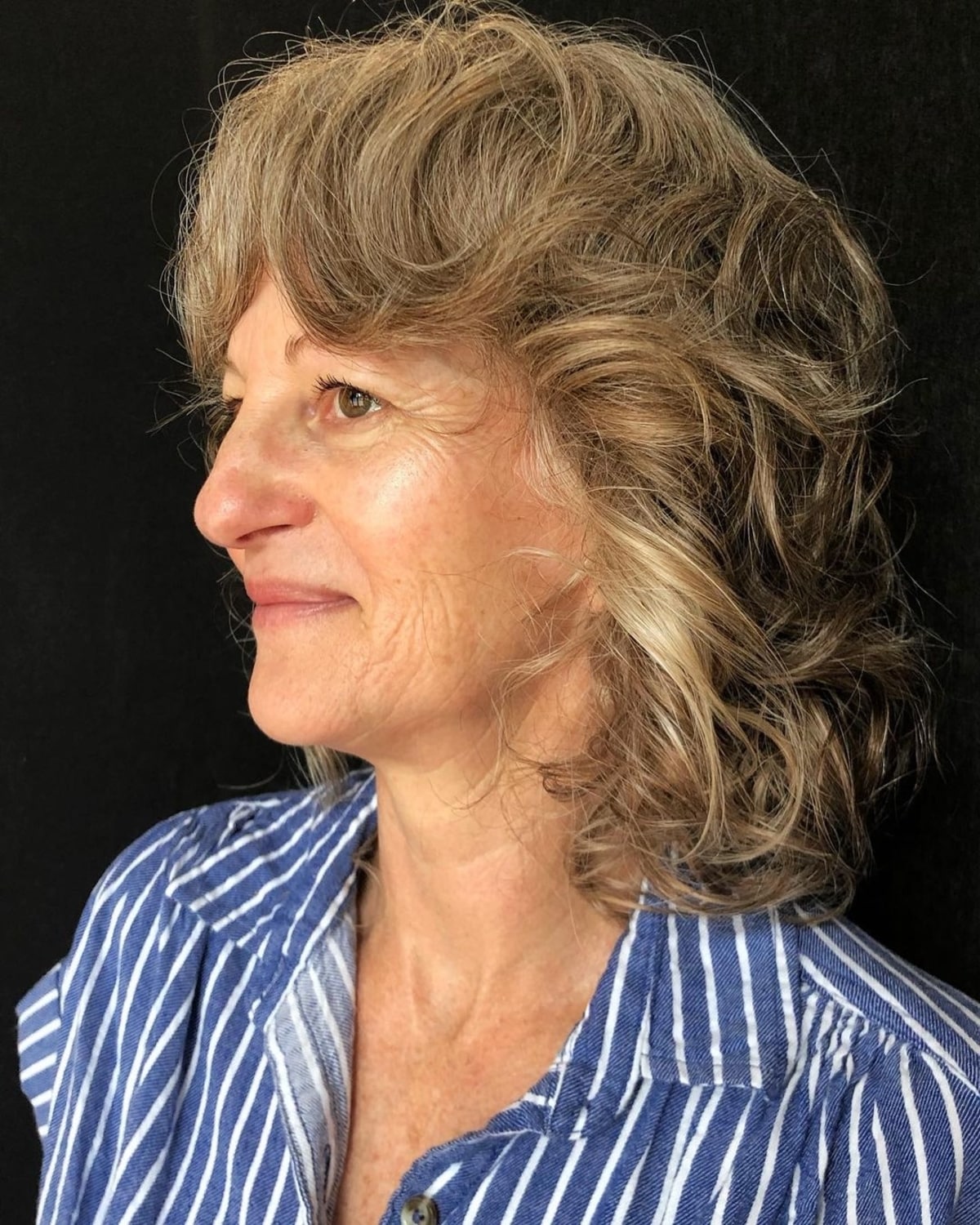 Coiffure ondulée volumineuse avec des mèches en plumes