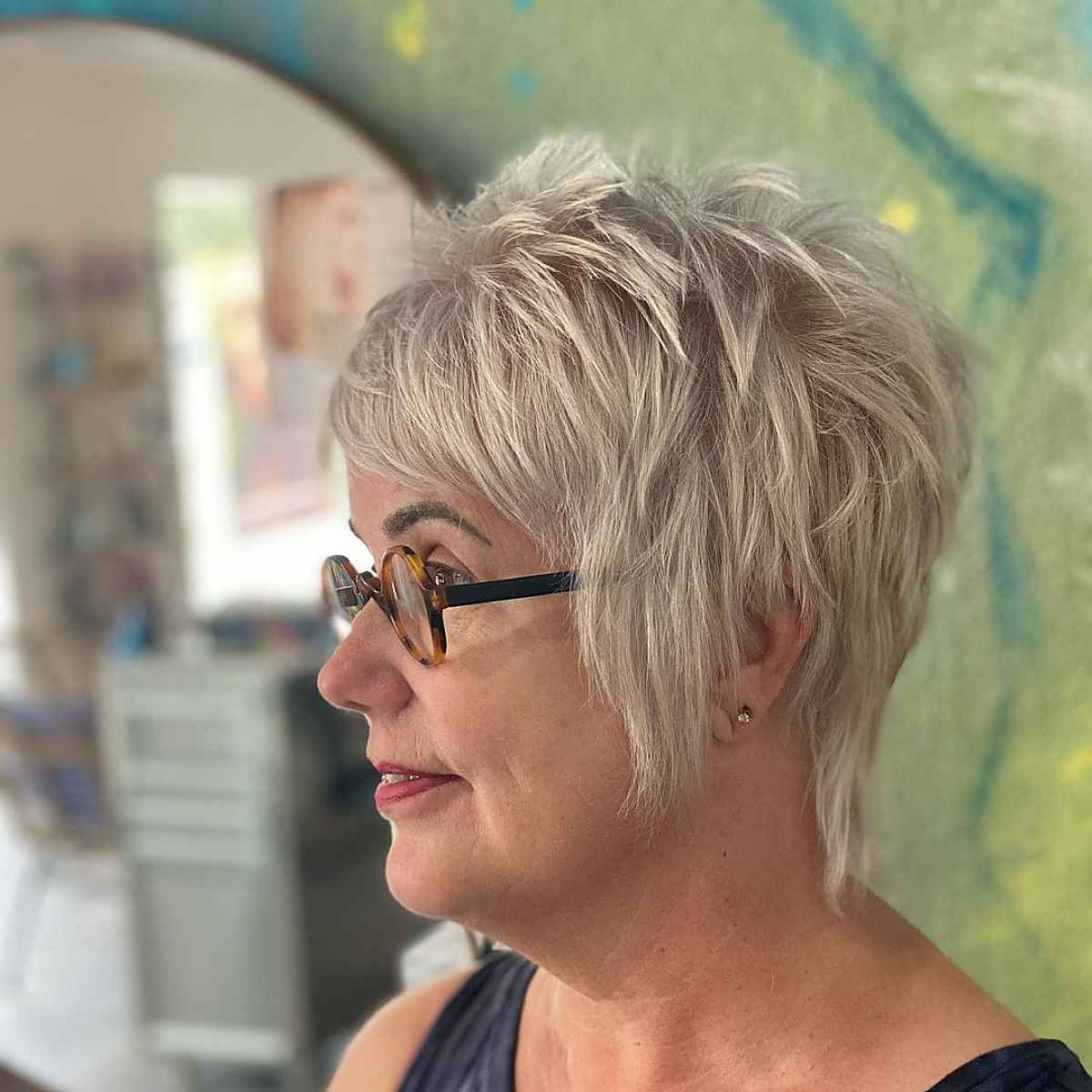 Cheveux courts pour les femmes de plus de 60 ans avec une frange et des lunettes.