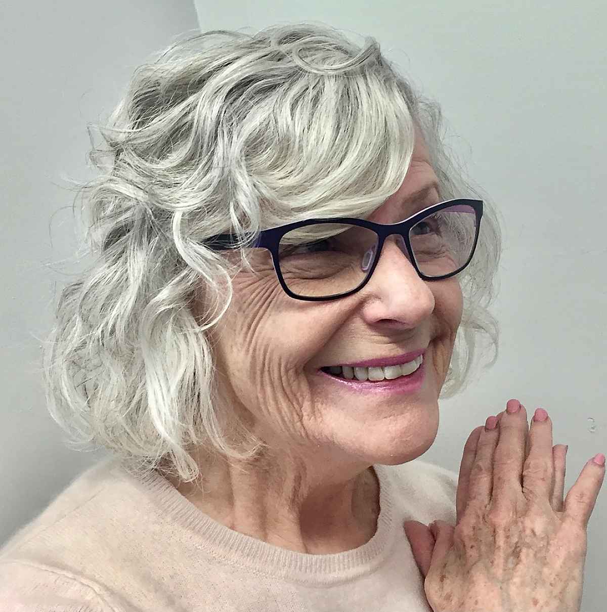 Coupe ondulée avec frange pour les femmes de plus de 70 ans portant des lunettes.